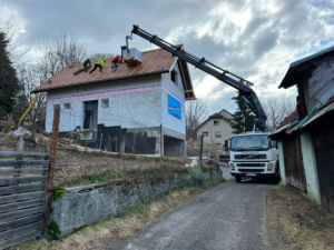 Nákladné vozidlo s hydraulickou rukou pri práci na budove