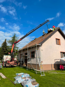 Autožeriav pri zdvíhaní materiálu na strechu domu